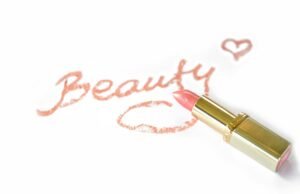 Close-up of pink lipstick next to 'Beauty' written on paper with a heart.